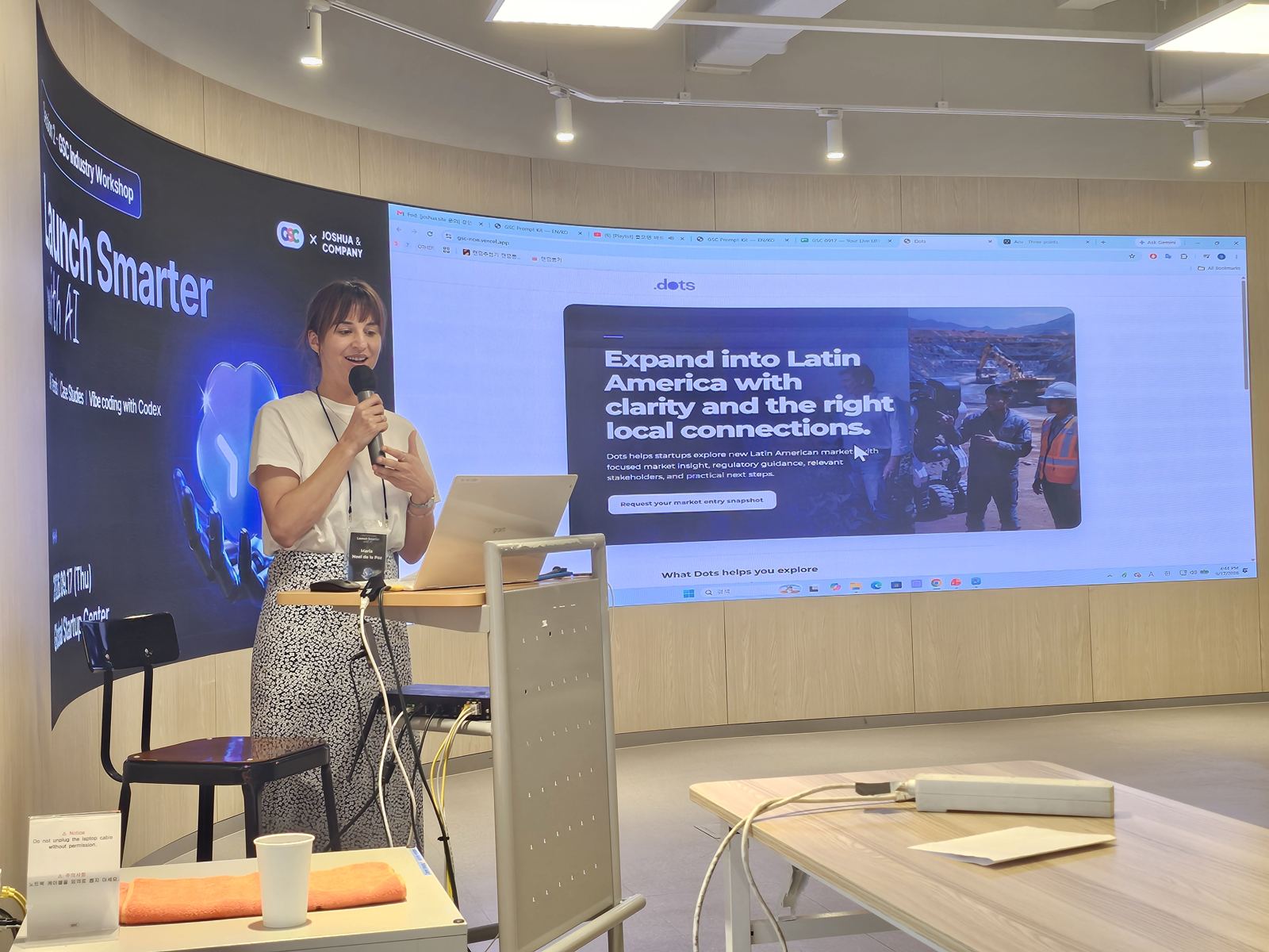 'Expand into Latin America' 화면 앞에서 참가자가 마이크를 들고 발표하고 있다